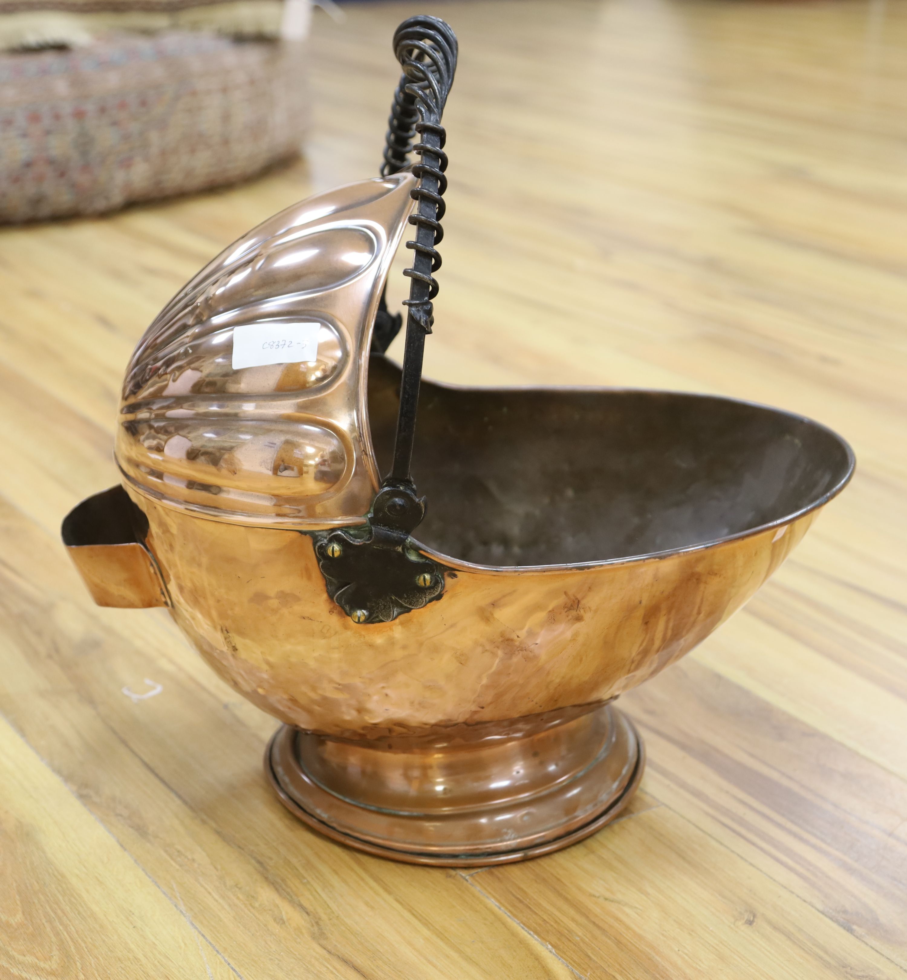 An Arts & Crafts planished copper coal scuttle, with wrought iron handle